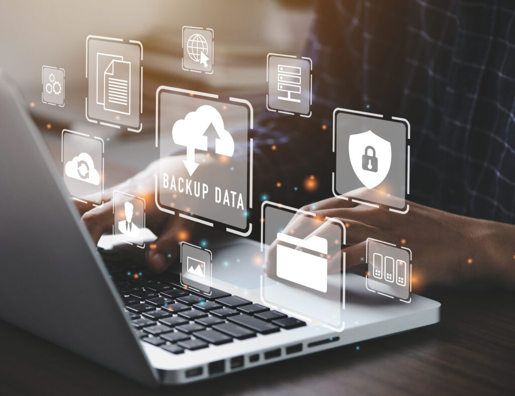 A man typing on a laptop with icons floating above it.